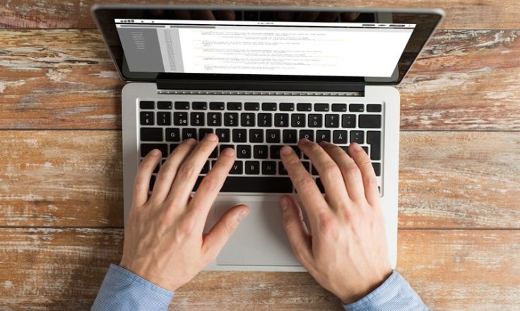 overhead image of hands typing on a laptop