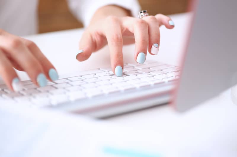 woman's hands typing on a keyboard while doing keyword research