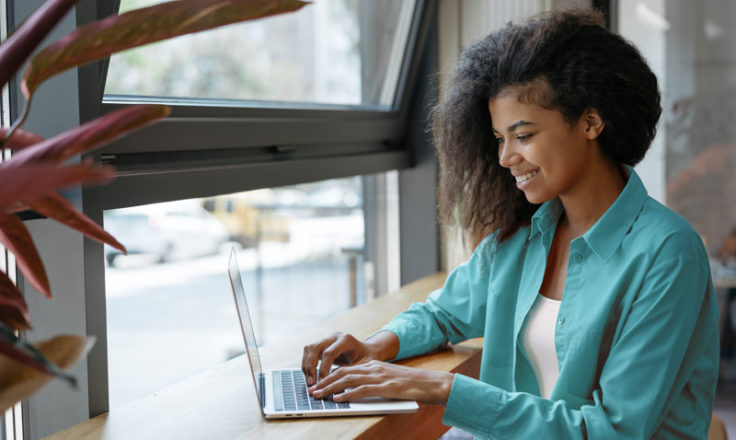 woman using a laptop by a window