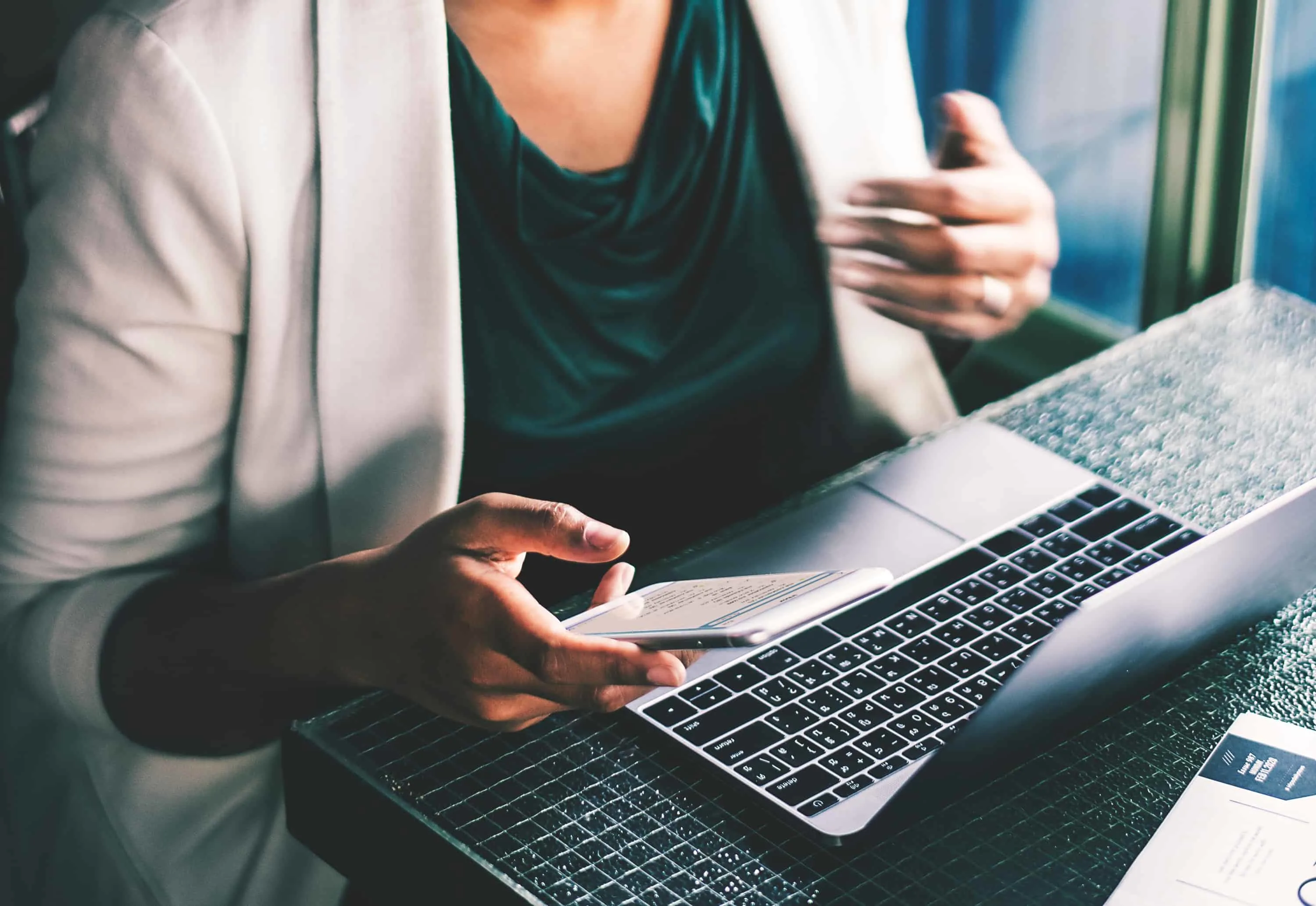 A woman using a computer and smart phone.