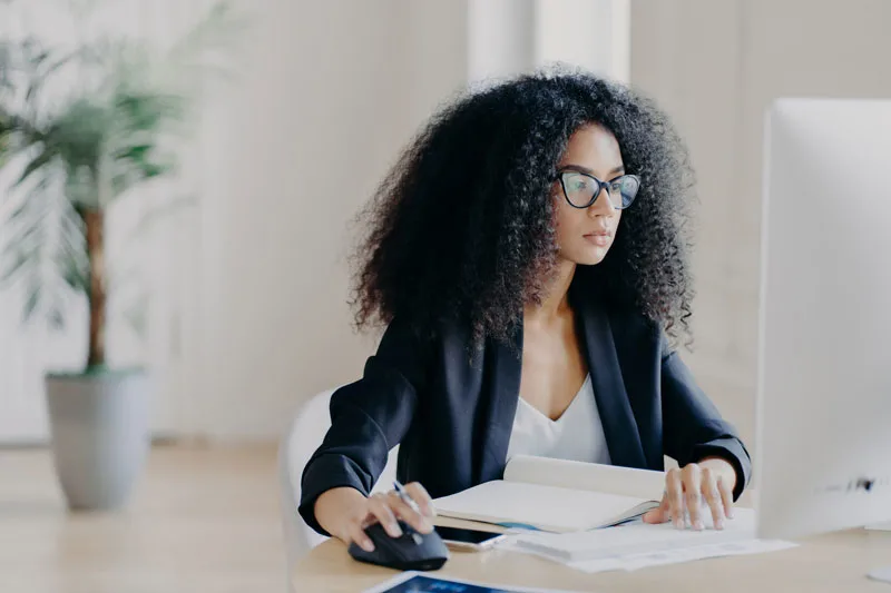 young woman in business attire working at a computer